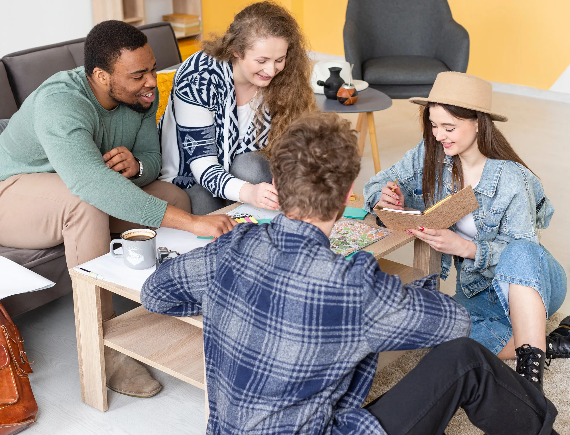 Group of young people chatting and taking notes in a bright living room