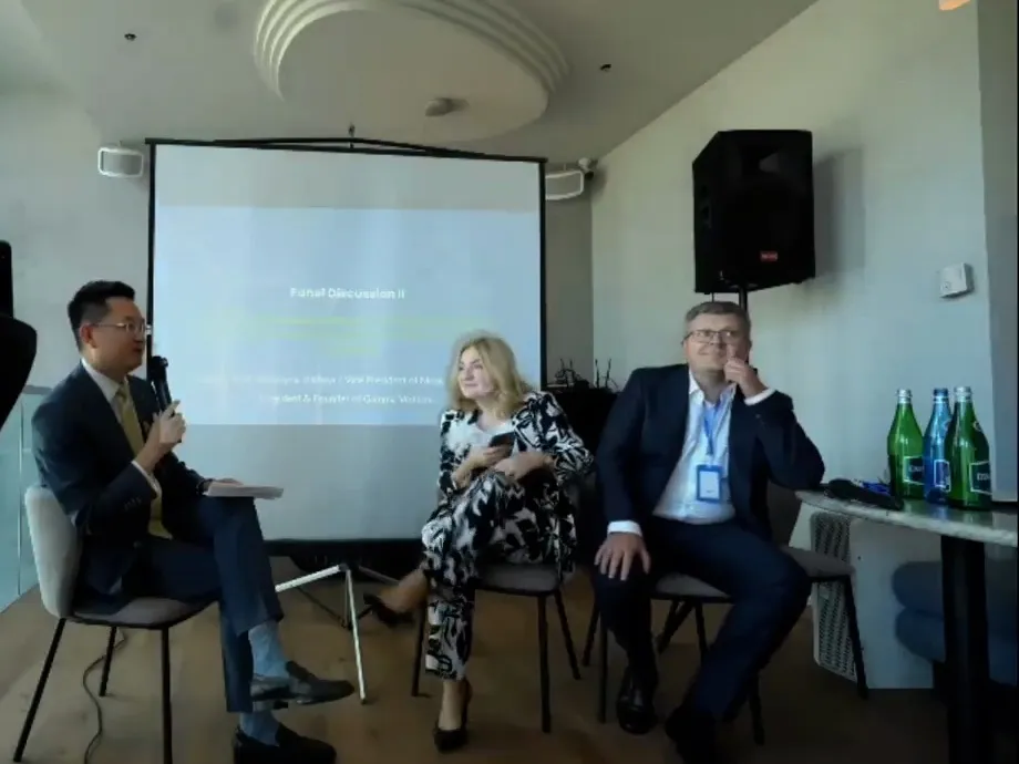 Trzyosobowy panel dyskusyjny przed ekranem na piętrze
