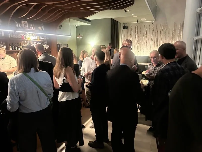 Pełna sala gości podczas networkingu na tle ściany z brzóz