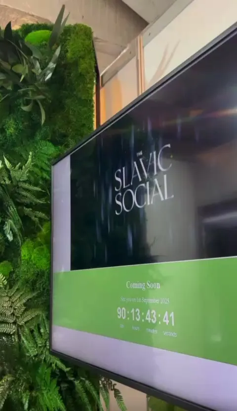 Screen showing The Slavic Social logo next to a green plant wall