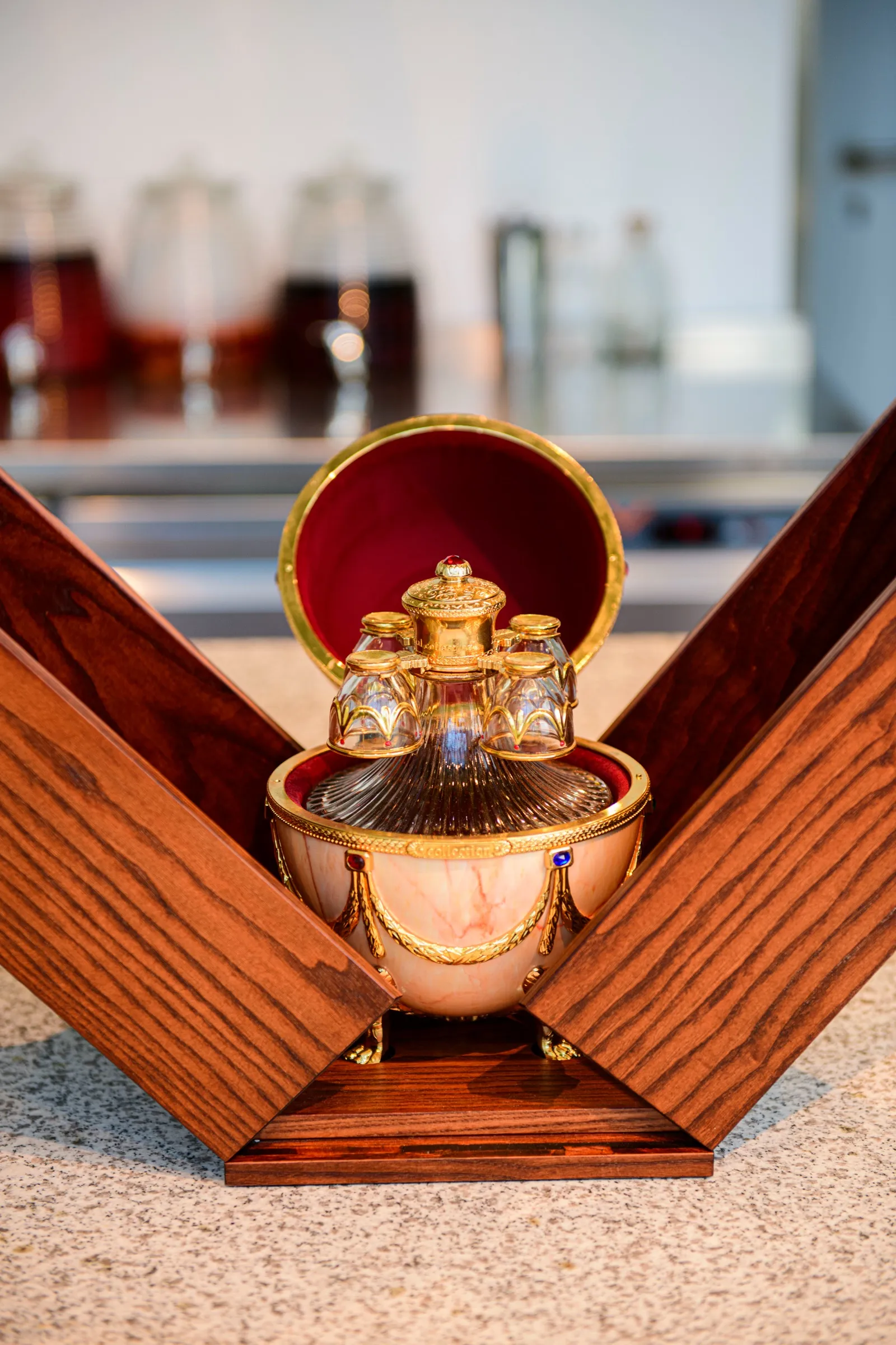 Egg-shaped decanter set with four gilded cups in an open wooden case on the Bar Lab counter
